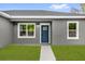 Close-up of a stylish front door with glass panes, framed by white trim and two windows, creating a welcoming entrance at 23 Fisher Run, Ocklawaha, FL 32179