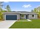 Charming single-story home featuring a well-manicured lawn, a blue door, and a two-car garage, offering great curb appeal at 23 Fisher Run, Ocklawaha, FL 32179