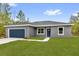 Beautiful home with a well-maintained lawn, a blue door, and a convenient two-car garage, creating a welcoming facade at 23 Fisher Run, Ocklawaha, FL 32179