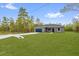 Appealing home features a spacious front yard, a two-car garage, and a classic design, set against a backdrop of trees at 23 Fisher Run, Ocklawaha, FL 32179