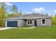 Inviting single-level home boasting a lush green lawn, stylish gray exterior, and a blue garage door, perfect for families at 23 Fisher Run, Ocklawaha, FL 32179