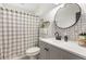 Cozy bathroom featuring a gray vanity, circular mirror, and patterned shower curtain at 337 Ohio Ave, St Cloud, FL 34769