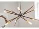 A modern starburst chandelier features gold and dark metal rods with lights, providing a bright and stylish focal point at 3964 Lightning Ct, Sanford, FL 32773