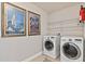 Efficient laundry room with modern washer and dryer, decorative wall art and storage shelves at 420 Lone Heron Way, Winter Garden, FL 34787