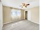 A spacious bedroom offers neutral walls, carpet, a ceiling fan, a closet, and window with sheer curtains at 46 Morning Glory Dr, Debary, FL 32713