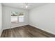 A simple bedroom with wood-look flooring and a large window for natural light at 5600 Revelwood Loop, Winter Park, FL 32792