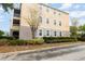 Exterior view of a three-story condo with a parking area and landscaped hedges at 6412 Queens Borough Ave # 215, Orlando, FL 32835