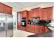 Well-lit kitchen featuring custom wood cabinets, stainless steel appliances, and black countertops at 7419 Gathering Ct, Reunion, FL 34747