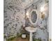 Charming powder room with decorative wallpaper, ornate mirror, and vintage-style fixtures at 906 Blue Sage St, Kissimmee, FL 34747