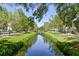 Picturesque street view with a central waterway, green lawns, mature trees, and sidewalks at 906 Blue Sage St, Kissimmee, FL 34747