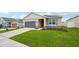 Single-Gathering home featuring a grey two-car garage, stone veneer accents, and lush green lawn at 1210 Normandy Dr, Haines City, FL 33844