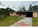 Cozy single-story home featuring a covered porch and driveway with colorful detailing on an overcast day at 1246 Rhodes Ct, Orlando, FL 32808