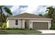 Charming single-story home featuring a neutral color scheme, a two-car garage, and a well-maintained lawn with tropical landscaping at 1718 Blue Lagoon Cir, Mascotte, FL 34753