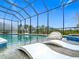 Enclosed pool with lounge chairs, basketball hoop, and view of the wooded landscape beyond at 1739 Oak Blossom Dr, Davenport, FL 33837