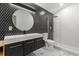 Modern bathroom with black hexagon tile wall, round mirror, and glass shower at 1899 Valley Wood Way, Lake Mary, FL 32746