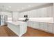 Well-lit kitchen with white cabinets, an island with seating, stainless steel appliances, and hardwood floors at 2341 Oleander Rd, Deland, FL 32724