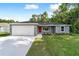 Charming single-story home featuring a red door, a two-car garage, and a well-manicured lawn at 23741 Sw Blueberry Ln, Dunnellon, FL 34431