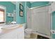 Well-lit bathroom with a glass-enclosed shower, white vanity, and teal walls with decorative paintings at 2546 Maneshaw Ln, Kissimmee, FL 34747