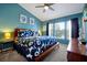 Bright bedroom featuring a ceiling fan, large window, and a bed with blue floral bedding at 2546 Maneshaw Ln, Kissimmee, FL 34747