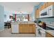 Modern kitchen with wood cabinets, white appliances, and open layout to dining area at 2546 Maneshaw Ln, Kissimmee, FL 34747