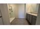 Bathroom with a tiled walk-in shower and a vanity with gray cabinets at 2597 Shamrock St, Tavares, FL 32778