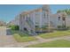 A view of a two-story condo with light blue siding, green shrubbery, stairway to the upper floor and well maintained lawn at 2742 Rio Grande Trl, Kissimmee, FL 34741