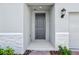 Stylish gray front door with a modern lantern, complemented by stone accents and lush landscaping at 4544 Windy Oak Way, St Cloud, FL 34772