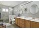 Bright bathroom featuring a double vanity, wood cabinets, and a glass enclosed shower with gray stone-look tiling at 4638 Destrehan, Leesburg, FL 34748