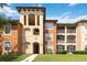 Exterior view of a multi-story condo building with a well-manicured lawn and tasteful neutral exterior tones at 5512 Metrowest Blvd # 203, Orlando, FL 32811