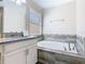 Well-lit bathroom featuring a soaking tub with tiled surround and a modern vanity at 5528 Solterra Cir, Davenport, FL 33837