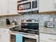 Close-up of a modern kitchen featuring stainless steel appliances and mosaic tile backsplash at 5528 Solterra Cir, Davenport, FL 33837