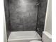 Bathroom featuring a white tub with dark marbled tile surround and modern fixtures at 635 Malaga Ave, Deltona, FL 32725