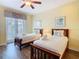 Cozy bedroom with two beds, neutral walls, wood floors, and natural light at 7407 Excitement Dr, Reunion, FL 34747