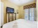 Comfortable bedroom featuring stylish furniture, a television and access to a patio at 7407 Excitement Dr, Reunion, FL 34747