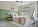 Stylish bedroom with green accent wall, pink and white decor, window with lots of sunlight, and side desk at 9888 Mere Pkwy, Orlando, FL 32832