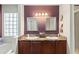 Bathroom with a tub and shower, double sinks, granite countertops, and dark wooden cabinets at 10783 Satinwood Cir, Orlando, FL 32825
