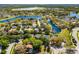 Scenic aerial view of a neighborhood with mature trees, a winding road, and a serene lake in the background at 12712 Forestedge Cir, Orlando, FL 32828