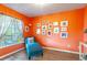 Comfortable bedroom with bright orange walls, a cozy chaise lounge, and natural light from the window at 1272 Mount Logan Dr, Apopka, FL 32712