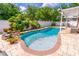 Backyard pool with a rock waterfall feature, surrounded by lush landscaping and a paved patio area at 1272 Mount Logan Dr, Apopka, FL 32712