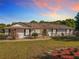 Charming single-story home featuring a red door, well-maintained lawn, and beautiful landscaping at 133 Orange Ridge Dr, Longwood, FL 32779