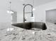 Close-up of kitchen sink with stainless steel faucet and granite countertop and open floor plan at 16121 Sw 37Th Terrace Rd, Ocala, FL 34473