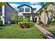 Charming two-story home features a well-manicured lawn, lush landscaping, and a welcoming brick pathway to the front porch at 17055 Wynford Ln, Winter Garden, FL 34787