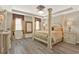 Luxurious main bedroom featuring a four-poster bed, elegant decor, tray ceiling, and hardwood floors at 17055 Wynford Ln, Winter Garden, FL 34787