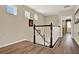Staircase with wooden floors and a dark wood and white banister, leading to the upstairs of this bright home at 17055 Wynford Ln, Winter Garden, FL 34787