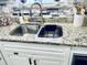 A kitchen sink features granite countertops, stainless steel basin, and stone backsplash at 1795 Orange View Ct, Kissimmee, FL 34746