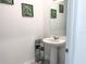 Modern half bathroom with a pedestal sink, decorative leaf art, and fresh paint at 1902 Presley Pl, Kissimmee, FL 34746