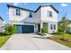 Charming two-story home with a blue garage door, landscaped yard, and a combination of white and gray siding at 2126 Derwent Dr, Davenport, FL 33896