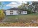 Expansive backyard with a stucco home, sliding glass doors, and an open grassy area bordered by mature trees at 250 Lakeridge Ct, Winter Springs, FL 32708