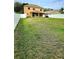 Wide backyard featuring green grass, a house, and a white fence at 25012 Chipshot Ct, Sorrento, FL 32776