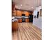 Kitchen with wood cabinets, black appliances, light brown wood flooring, and stylish pendant lights at 25012 Chipshot Ct, Sorrento, FL 32776